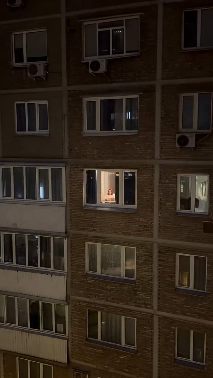 The camera finds a lit window at night.