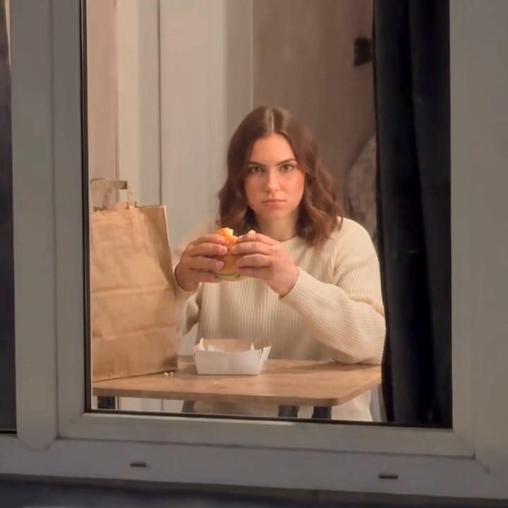 A person at a lit window, seen from outside at night